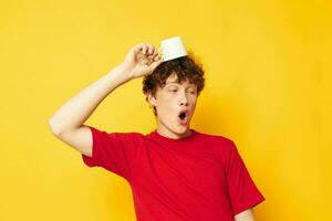 portrait of a young curly man in a red T-shirt with a white cap in his hands isolated background unaltered photo