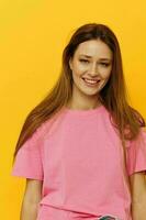 portrait of a young woman pink t-shirts and denim shorts posing yellow background photo