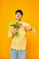 Photo of romantic young boyfriend with a bouquet of flowers posing a gift yellow background unaltered