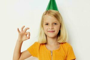 un niña con un verde gorra en su cabeza gestos con su manos foto