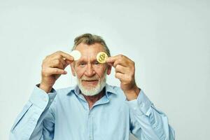 Portrait of happy senior man finance gold coins bitcoin near face isolated background photo