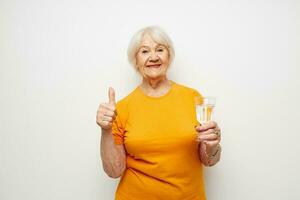 smiling elderly woman in casual t-shirt glasses glass of water isolated background photo