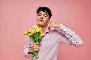 portrait of a young man in a pink shirt with a bouquet of flowers gesturing with his hands Lifestyle unaltered photo