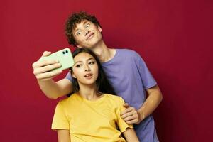 Man and woman in colorful T-shirts with a phone isolated background photo