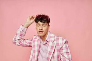 A young man pink glasses checkered jacket fashion posing pink background unaltered photo