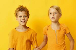 Cute preschool kids in yellow t-shirts standing side by side childhood emotions yellow background unaltered photo