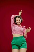 cheerful woman in green shorts listening to music on headphones photo