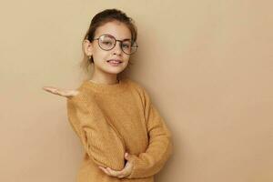 Portrait of happy smiling child girl with glasses emotions gesture hands beige background photo