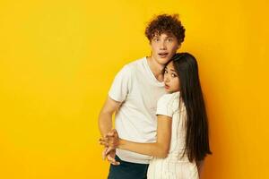 teenagers stand hugging each other in white T-shirts yellow background unaltered photo