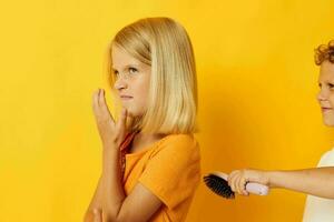 a boy with a comb combing a girl's hair yellow background photo