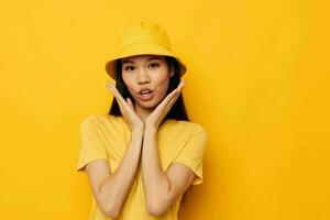 mujer con asiático apariencia en un amarillo camiseta y sombrero posando emociones aislado antecedentes inalterado foto