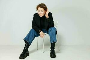 portrait of a young woman black jacket jeans posing light background unaltered photo