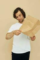 Cheerful man in a white T-shirt with paper bag beige background photo