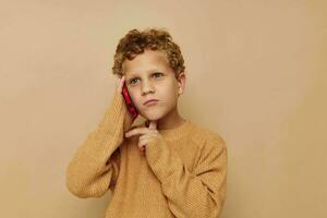 pequeño chico en un suéter hablando en el teléfono foto