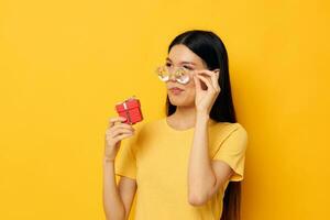 woman with Asian appearance with gift boxes in hands fun posing yellow background unaltered photo