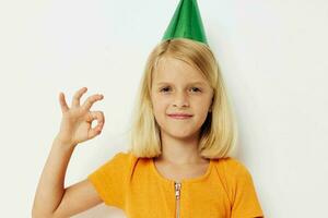 un niña con un verde gorra en su cabeza gestos con su manos foto