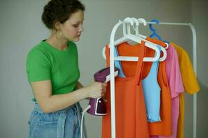 cheerful woman ironing clothes on a hanger wardrobe isolated backgrounds unaltered photo