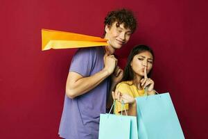 cute young couple in colorful T-shirts with bags Shopping red background unaltered photo