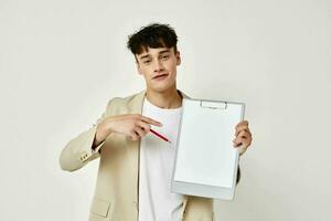 handsome guy posing with a notepad in a suit light background unaltered photo