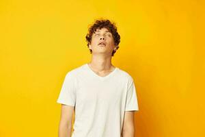 curly red-haired guy in a white t-shirt on a yellow background photo