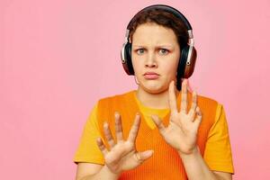 beautiful woman listening to music with headphones orange sweater emotions fun cropped view unaltered photo