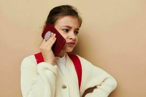 bonito joven niña hablando en el teléfono con un mochila beige antecedentes foto