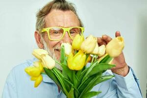 old man in a blue shirt with a bouquet of flowers light background photo