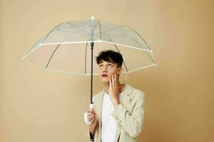 a man with an open umbrella in a jacket protection from the rain beige background photo