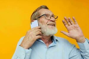 retrato mayor hombre en un azul camisa y lentes hablando en el teléfono inalterado foto