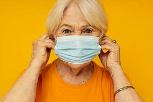 smiling elderly woman in casual t-shirt medical mask yellow background photo