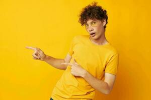 retrato de un joven Rizado hombre amarillo camiseta lentes Moda mano gestos aislado antecedentes inalterado foto