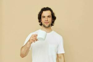 man in a white T-shirt with a mug in hand isolated background photo