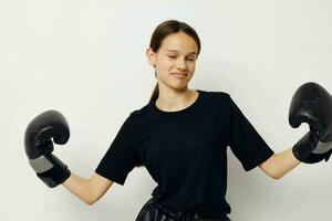 joven hermosa mujer en boxeo guantes en negro pantalones y un camiseta ligero antecedentes foto