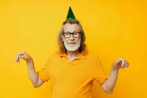 retrato mayor hombre en un amarillo camiseta con un gorra en su cabeza divertido amarillo antecedentes foto