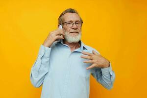 retrato de contento mayor hombre en un azul camisa y lentes hablando en el teléfono recortado ver foto
