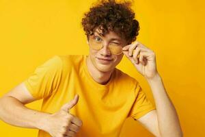 Young curly-haired man wearing stylish glasses yellow t-shirt posing monochrome shot photo