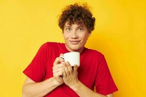 cute red-haired guy in a red T-shirt with a white cap in his hands isolated background unaltered photo