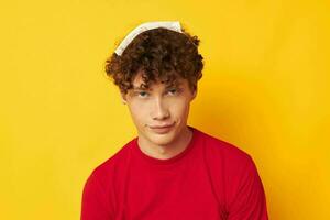 guy with red curly hair wearing a red t-shirt medical mask on the face posing yellow background unaltered photo