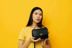 alegre mujer en un amarillo camiseta negro De las mujeres bolso foto