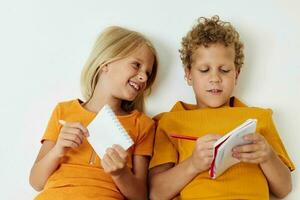 Boy and girl lie on the floor with notepads and pencils childhood lifestyle unaltered photo