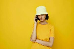 attractive woman yellow t-shirt and Hat summer style with phone isolated background photo