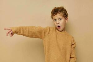 Rizado chico en un beige suéter posando divertido infancia inalterado foto