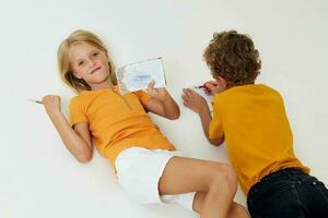 Boy and girl on the floor with notepads and pencils isolated background unaltered photo