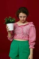 attractive young woman standin and holding flower in pot close-up unaltered photo