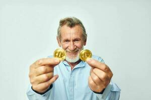 Senior grey-haired man cryptocurrency bitcoin face close up investment light background photo