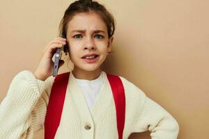 Portrait of happy smiling child girl with phone posing red backpack isolated background photo