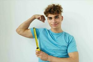 rizado chico azul camiseta medición cinta posando estilo de vida inalterado foto