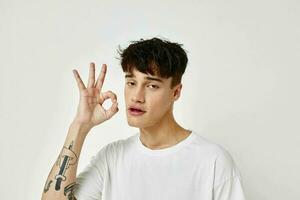 portrait of a young man tattoo on hands in white t-shirt light background unaltered photo