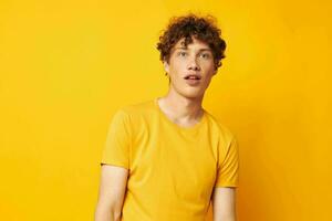 Young curly-haired man wearing stylish yellow t-shirt posing Lifestyle unaltered photo
