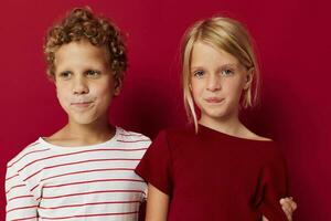 Portrait of cute children emotions stand side by side in everyday clothes red background photo